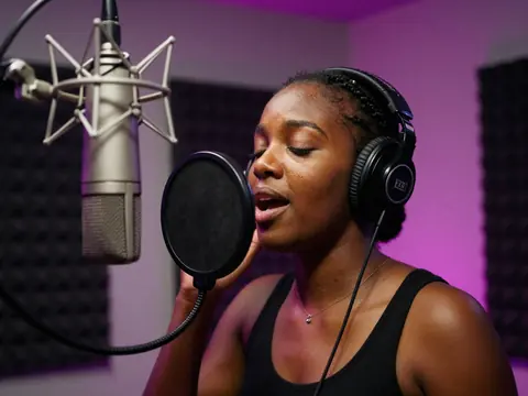 A singer records at the microphone in a music studio